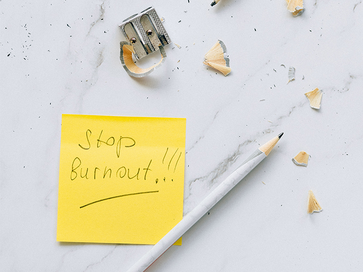 Zu sehen sind ein Bleistift, ein Anspitzer und ein Post-it mit dem Satz „Stop Burnout!“. Es geht um die Arbeitszeiterfassung. Bild: Pexels/Nataliya Vaitkevich