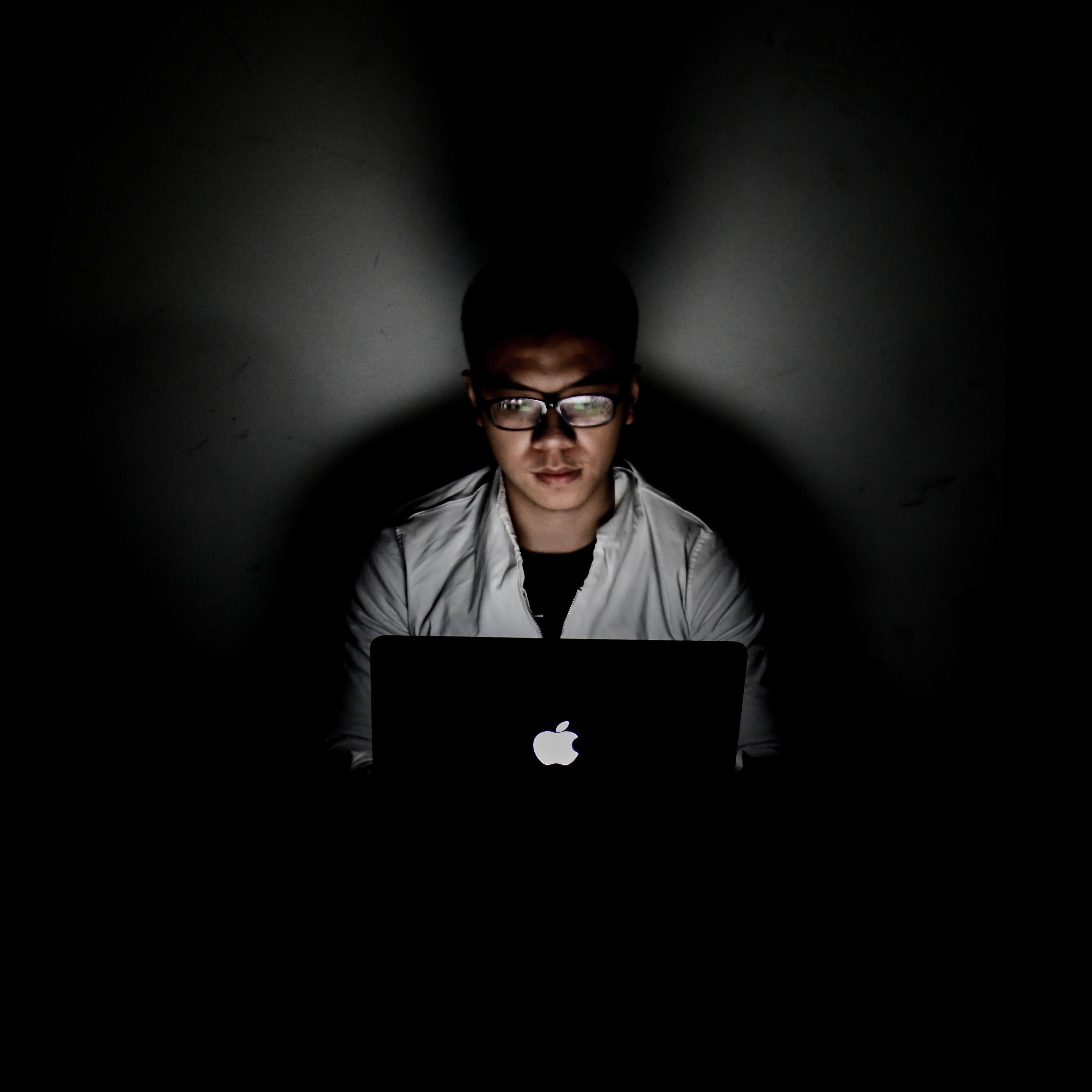 Zu sehen ist ein Mann in einem dunklen Raum. Licht, erzeugt durch einen Laptop-Bildschirm, fällt auf das Gesicht des Mannes. Vielleicht ist er ein Hacker und der Leitsatz „Hackback –Cyber-Abwehr proaktiv“ macht ihm Angst. Bild: www.unsplash.com / 广博 郝