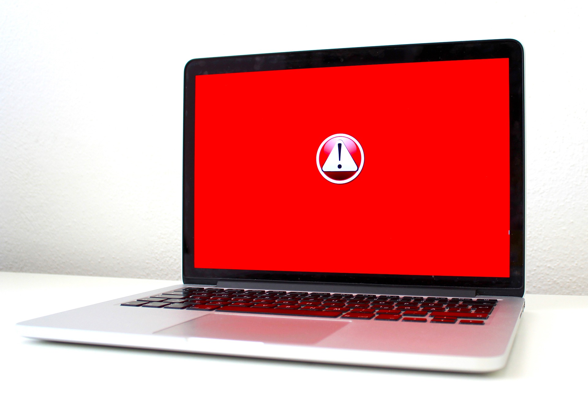 Zu sehen ist ein Laptop auf einem weißen Tisch vor weißem Hintergrund. Der Bildschirm ist rot und enthält einen Warnhinweis. Vielleicht ist der Laptop von der Ransomware GermanWiper befallen. Bild: www.pixabay.com / Michael Geiger