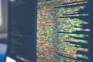 Zu sehen ist ein Monitor mit dem Code einer Software. Ob hier auf Security by Design geachtet wird? Bild: www.unsplash.com / Markus Spiske