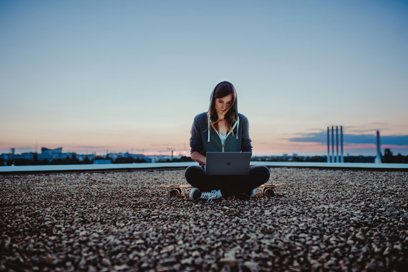Das Bild zeigt eine Frau, die auf einem Dach an ihrem Computer arbeitet – legal mit einer Microsoft-Lizenz. Bild: Microsoft / Julia Müller