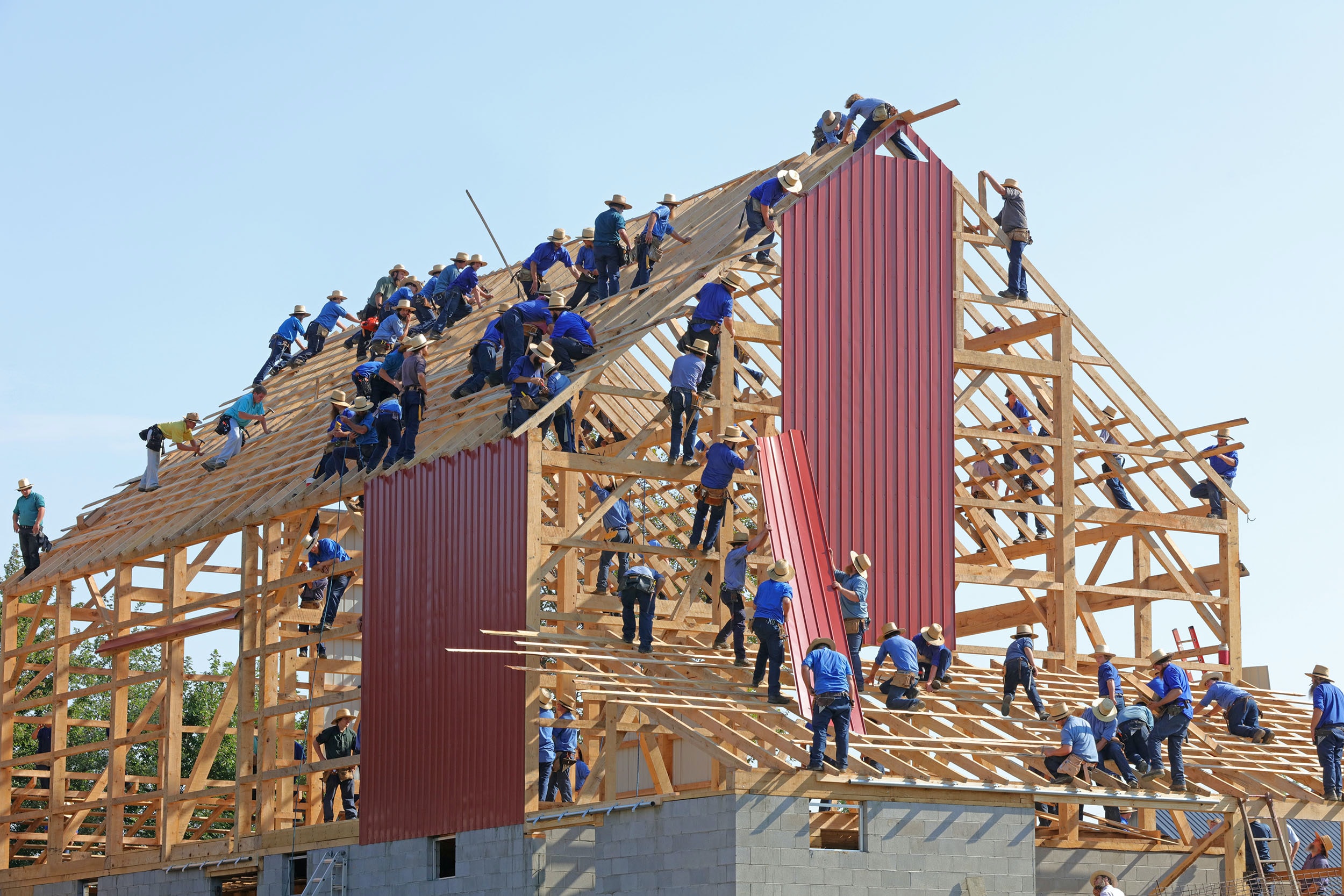 Das Bild zeigt viele Bauarbeiter, die gemeinsam an einem Haus bauen. Betriebsklima verbessern funktioniert auch hier mit entsprechen Mitarbeiter-Plattformen. Bild: Unsplash/Randy Fath