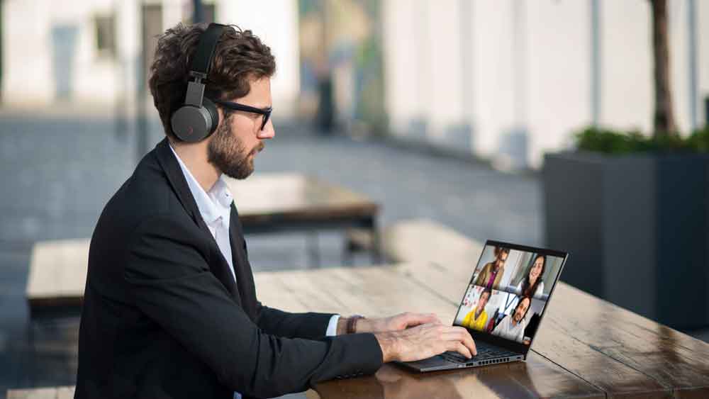 Das Bild zeigt einen Mann, der draußen ein Webmeeting durchführt. Die Home-Office-Produktivität wird durch gute Hardware gewährleistet. Bild: Lenovo