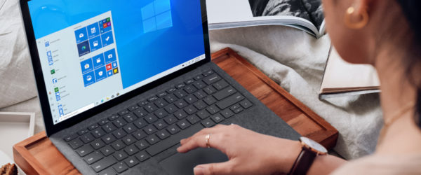Eine Frau nutzt Remote Work und hat ihren Laptop im Bett auf einem Tablett mit Füßen. Bild: Unsplash/Windows
