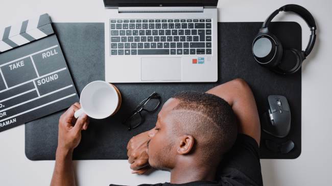 Zu sehen ist ein Mann, der vor seinem Laptop eingeschlafen ist. Er sollte sich die Frage stellen: Wie lange kann man Office 2010 noch nutzen? Bild: Unsplash/Nubelson Fernandes