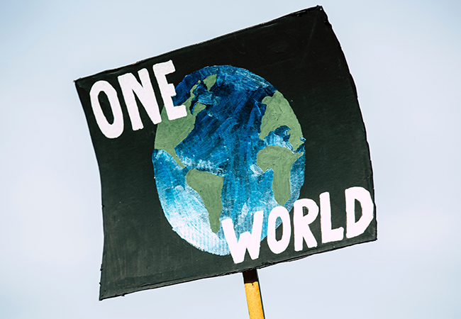 Zu sehen ist ein Protestschild mit dem Bild der Weltkugel und dem Schriftzug "One World". Es geht um Klimaneutralität. Bild: Pexels/Markus Spiske