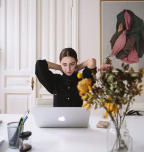 Eine Frau sitzt vor einem Laptop und greift sich in den Nacken. Ist sie verspannt, weil ihr Chef Mitarbeiter überwachen im Home Office gut findet? Bild: Pexels / Polina Zimmerman