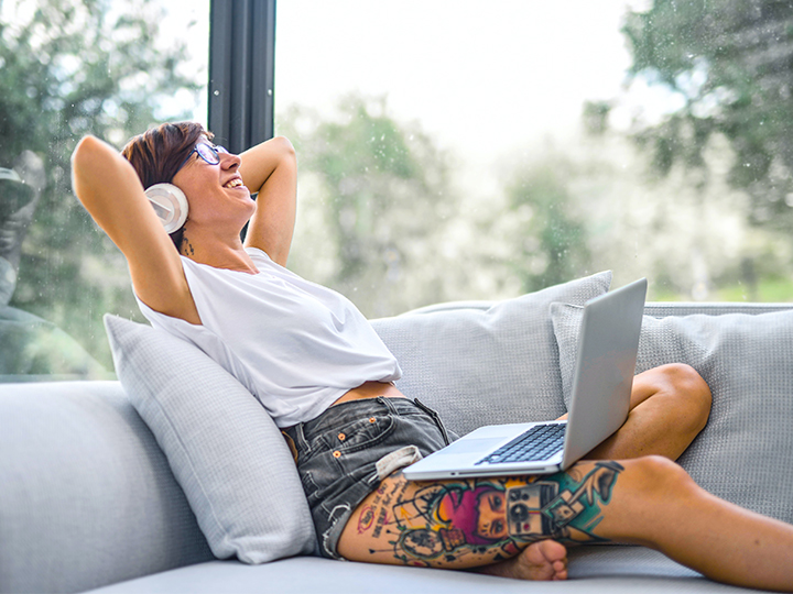 Eine Frau sitzt entspannt mit Laptop auf dem Sofa. So manche Arbeitgeber möchten Mitarbeiter überwachen im Home Office. Bild: Pexels/Andrea Piacquadio