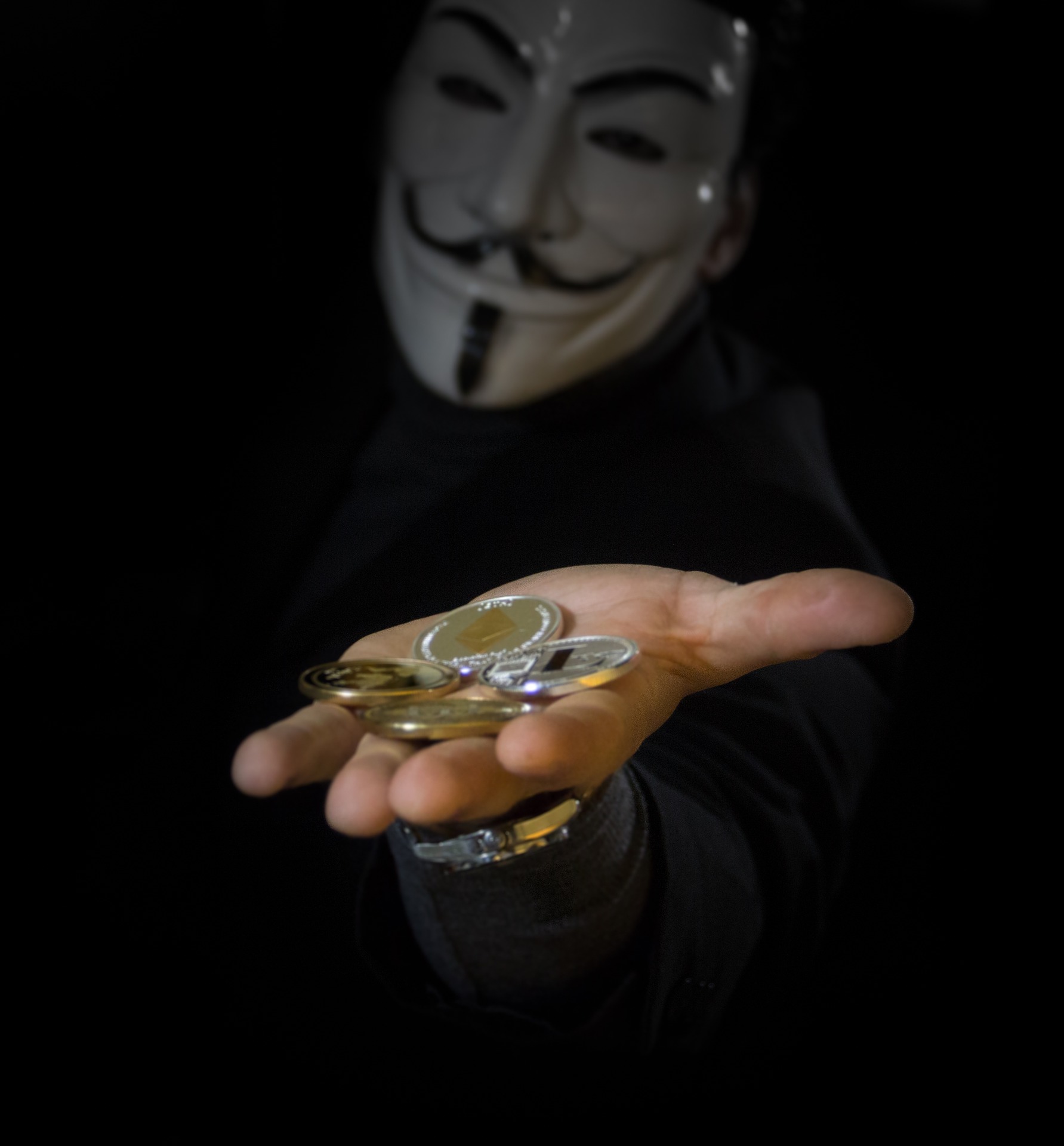 Zu sehen ist eine maskierte Person, die eine Hand mit Bitcoin-Münzen in die Kamera hält. Die Hintermänner der Clop-Ransomware fordern Lösegeld in Bitcoin. Bild: Pixabay / WorldSpectrum