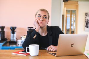 Eine Frau sitzt genervt im Home Office am Küchentisch. Sie ist kein Fan davon, aber muss die Pflicht zum Home Office für Arbeitnehmer einhalten. Bild: Unsplash/magnet.me