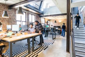 Zu sehen ist ein Büro mit mehreren PC-Arbeitsplätzen und Mitarbeitern. Sie fragen sich: Was ist ein IT-Systemhaus?