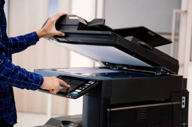 Zu sehen sind die Hände eines Mannes, der ein Multifunktionsdrucker mit Fax-Funktion verwendet. Es gibt Diskussionen im Datenschutz: Fax gilt als nicht DSGVO-konform. Bild: stock.adobe.com/kunakorn