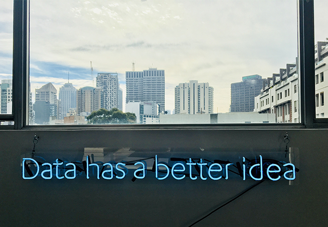 Zu sehen sind der Blick aus einem Fenster auf eine Skyline und der Schriftzug "Data has abetter idea". Es geht um Data Discovery. Bild: Unsplash/Franki Chamaki
