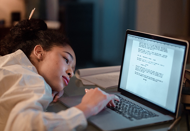 Ein Frau arbeitet lustlos am Laptop. Vielleicht kann Silent Coworking zu mehr Motivation im Home Office verhelfen. Bild: Pexels/Ron Lache