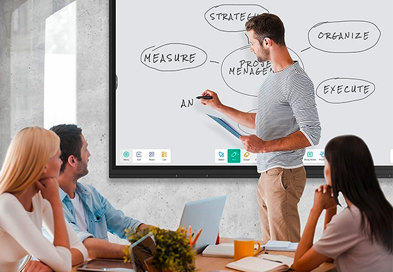 Zu sehen ist ein Team in einem Meeting-Raum, ein Mann nutzt für das kollaborative Arbeiten die Whiteboard-Funktion des Interactive Displays. Bild: iiyama