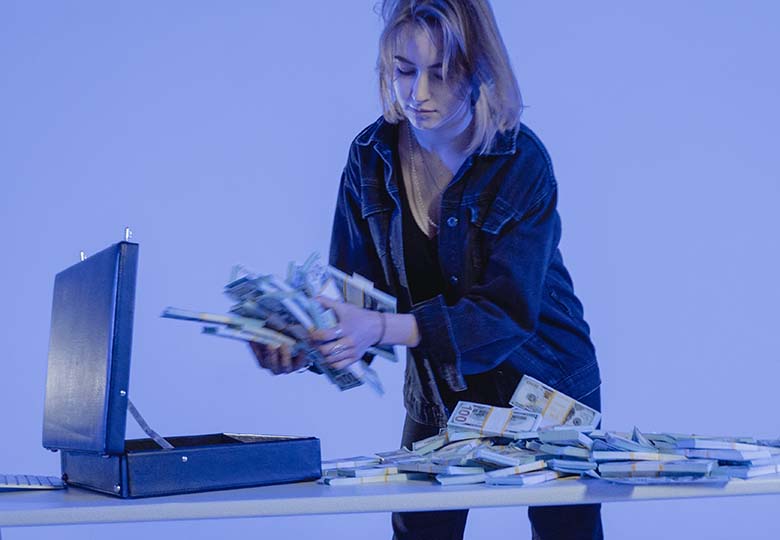 Eine Frau scheffelt Geld in einen Aktenkoffer. Der Verkauf von gestohlenen Daten im Darkweb ist lukrativ. Bild: Pexels/Tima Miroshnichenko