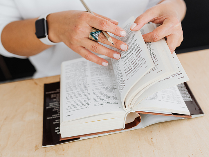 Hände blättern in einem Wörterbuch. Heute gibt es Übersetzungstools. Bild: Pexels/Karolina Grabowska