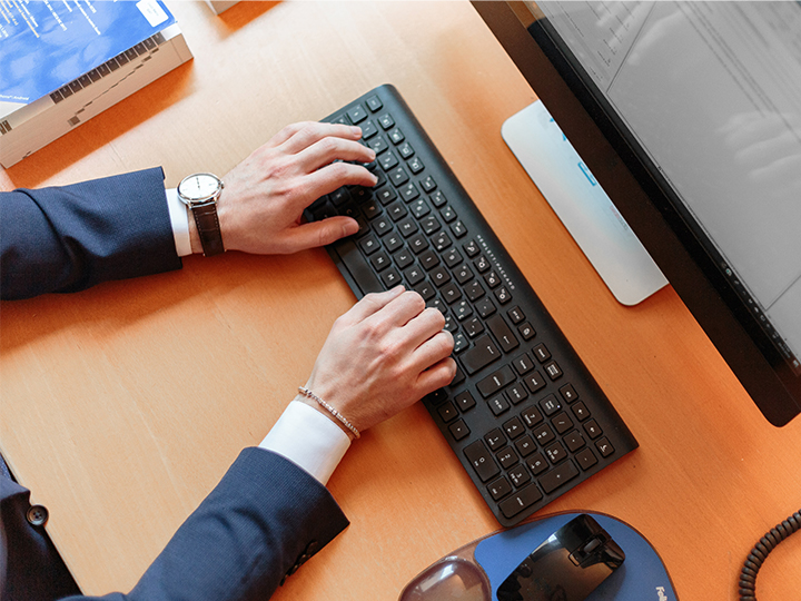 Hände in einem Anzug bedienen eine Computer-Tastatur. Das Gerät könnte durch die Malware Zloader infiziert sein. Bild: Pexels/Oleg Magni