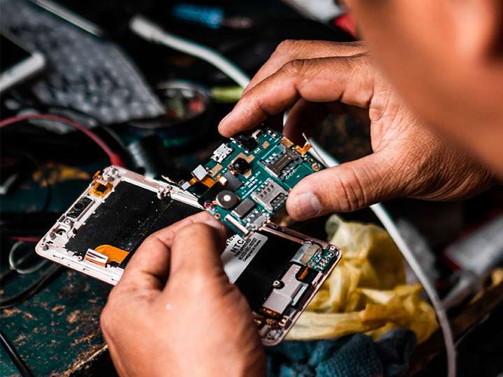 Zwei Hände reparieren das Innenleben eines Smartphones. Hier ist das Recht auf Reparatur umgesetzt. Bild: Unsplash/Clint Bustrillos