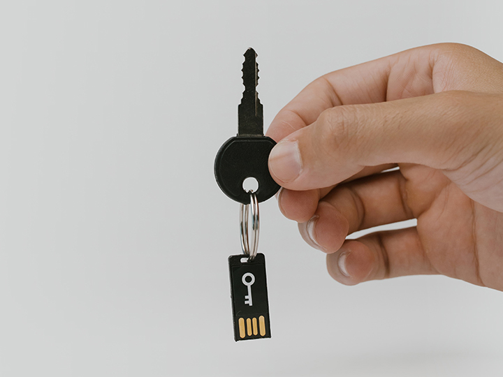 Eine Hand hält einen Schlüssel, an dem ein USB-Stick hängt. Es gibt USB-Sticks mit speziellen Verschlüsselungstechniken. Bild: Pexels/cottonbro