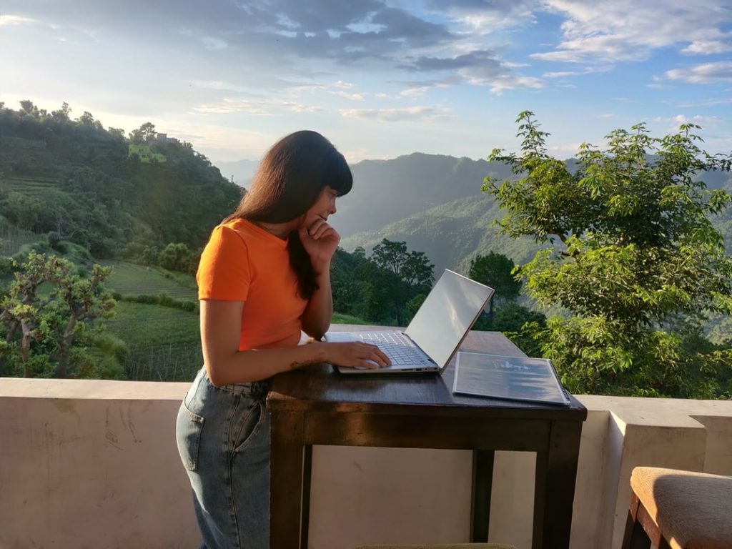 Eine Frau arbeitet auf ihrer Terrasse an ihrem Laptop.