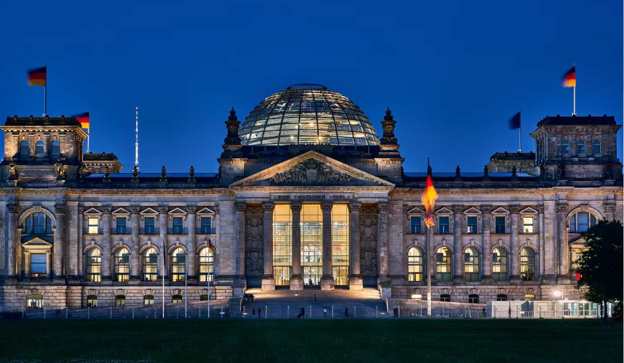 zu sehen ist das Reichstagsgebäude in Berlin bei Nacht. Thema des Artikels ist das neue Onlinezugangsgesetz. Bild: Unsplash/Norbert Braun