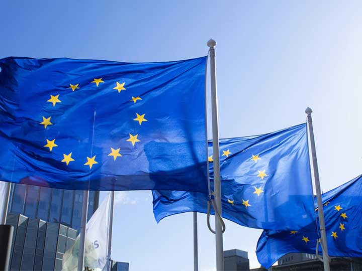 zu sehen sind drei Flaggen der EU im Wind. Thema ist der Status Quo der Digitalwirtschaft in Europa und der Cyber Resilience Act . Bild: Unsplash/Alexandre Lallemand