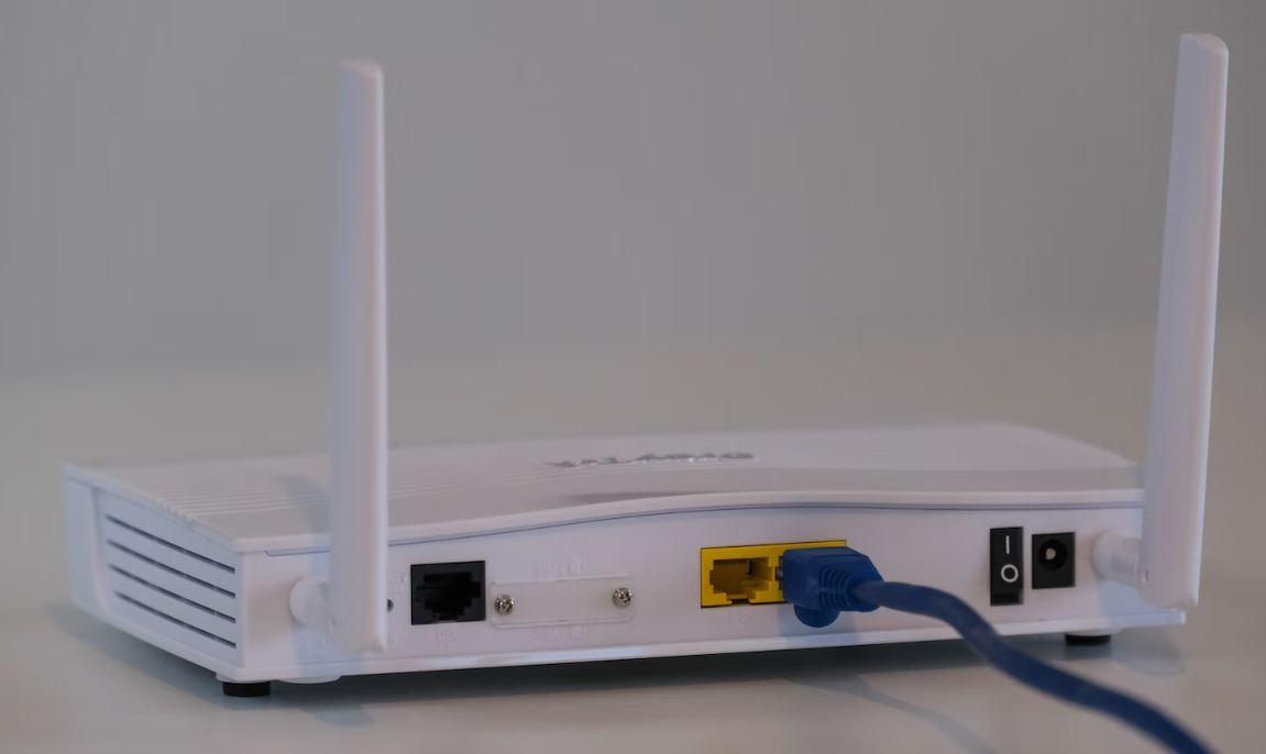 zu sehen ist ein weißer Router vor einer weißen Wand. Das Thema ist die Sicherheit von Firewalls innerhalb von Routern und die bessere Alternative, die UTM-Firewall. Bild: Unsplash/ Compare Fibre