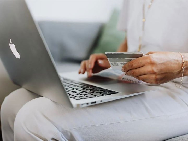 seit Juli muss es möglich sein, Verträge online kündigen zu können. zu sehen ist eine Frau, die mit ihrer Kreditkarte vor einem Laptop sitzt. Bild: Pexels/Karolina Grabowska