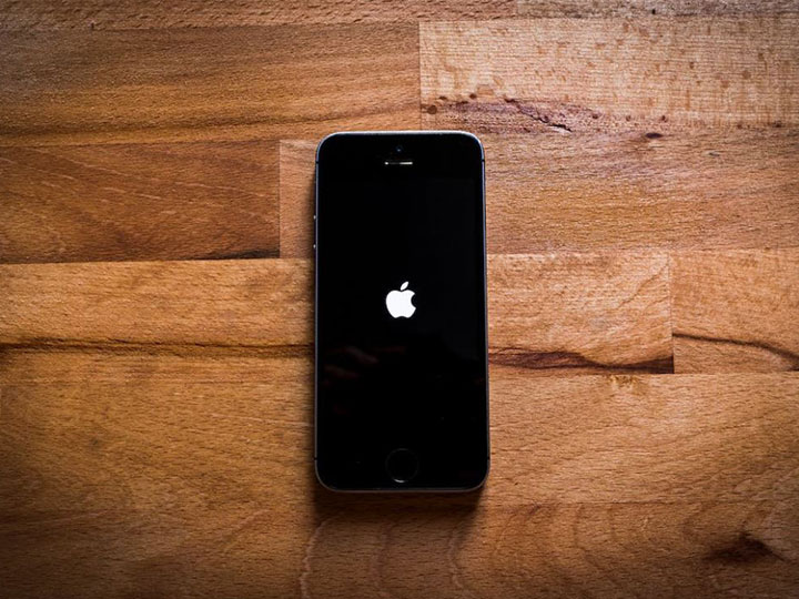 zu sehen ist ein iPhone mit Ladebildschirm beim Starten bei einem Holztisch. Bild: Pexels/Mateusz Dach. Thema Fast Identity online