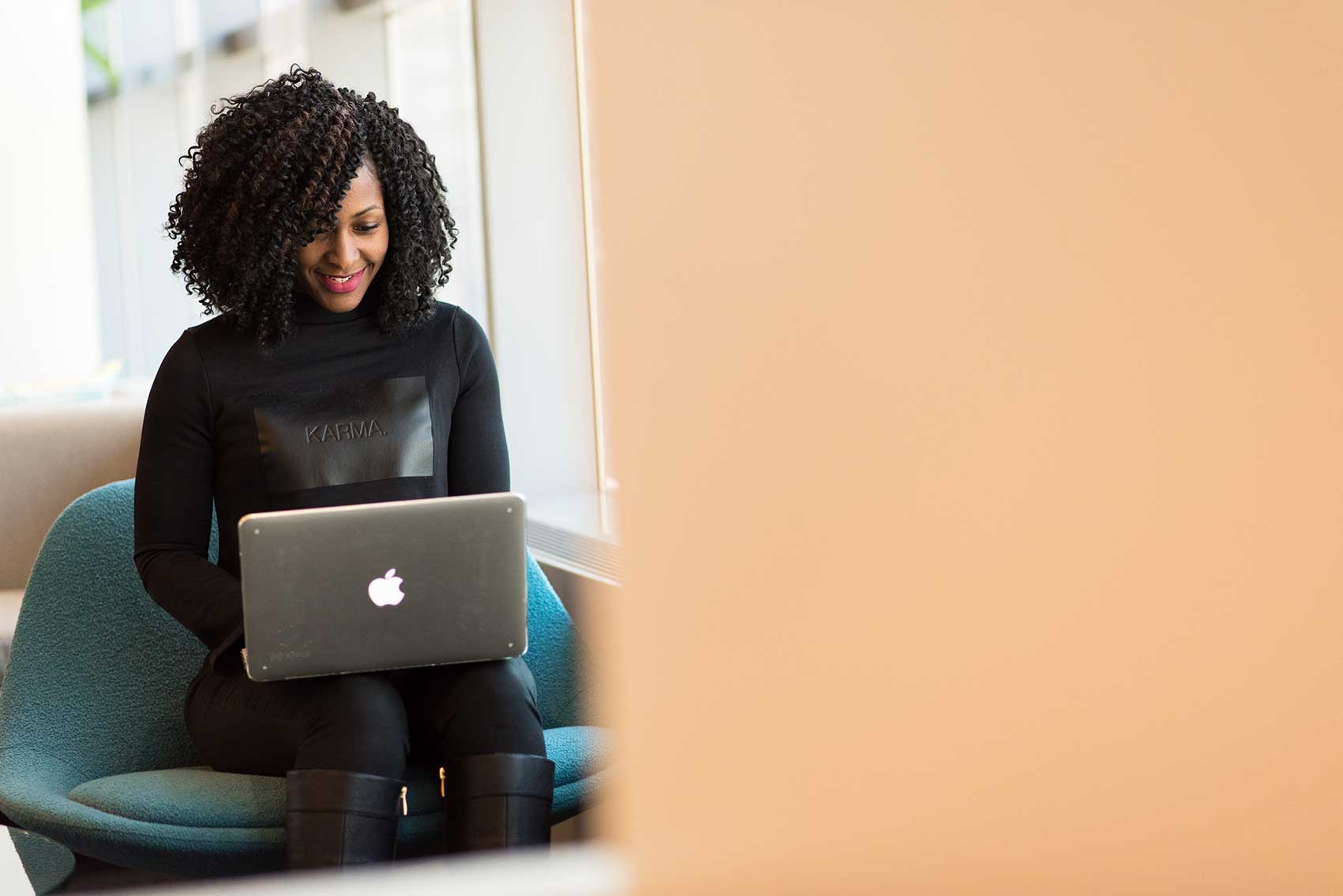 zu sehen ist eine Frau, die lächelnd an einem Macbook arbeitet. Das Thema sind die Vorteile einer Schwachstellenanalyse der IT. Bild: Pexels/Christina Morillo