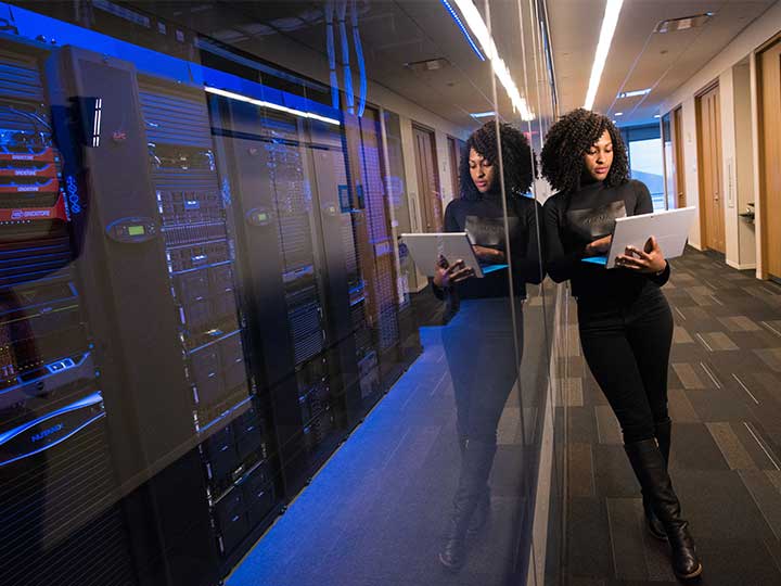 zu sehen ist eine Frau mit Laptop in einem Serverraum. Das Thema ist eine Schwachstellenanalyse zur Optimierung der IT-Sicherheit. Bild: Pexels/Christina Morillo