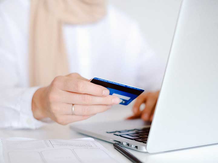 zu sehen ist eine Frau beim Online Shopping, die ihre Kreditkarte in der Hand hält. Thema ist der Fakeshop und wie man ihn erkennt. Bild: Pexels/Anna Shvets