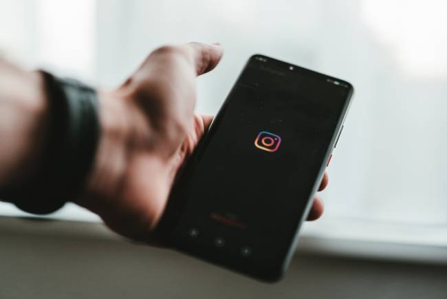 Eine Hand hält ein Handy, auf dem Instagram lädt. Es geht um Social Recruiting. Bild: Unsplash/Claudio Schwarz