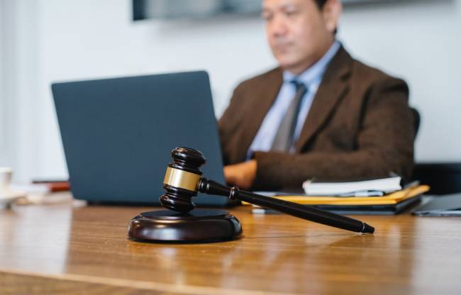 Zu sehen ist ein Anwalt am Laptop, im Vordergrund ein Richterhammer; es geht um das Hinweisgeberschutzgesetz. Bild: Pexels/Sora Shimazaki
