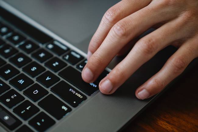 Eine Hand nutzt eine Laptop-Tastatur; möglicherweise nutzt hier jemand ein digitales Hinweisgebersystem. Bild: Pexels/Eren Li