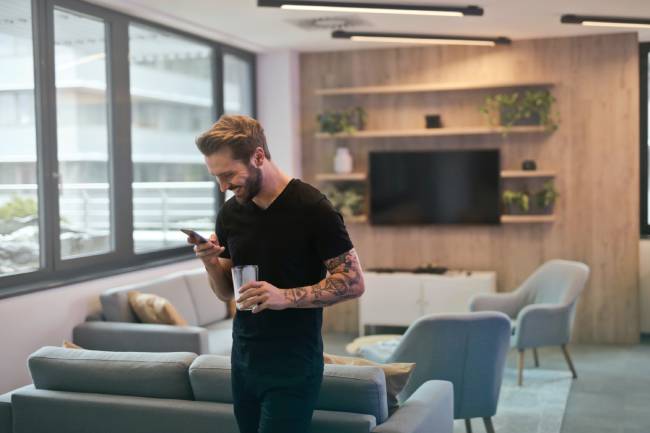 Zu sehen ist ein Mann in einem Meeting-Raum, der ein Smartphone nutzt - und Wifi 7? Bild: Pexels/Andrea Piacquadio