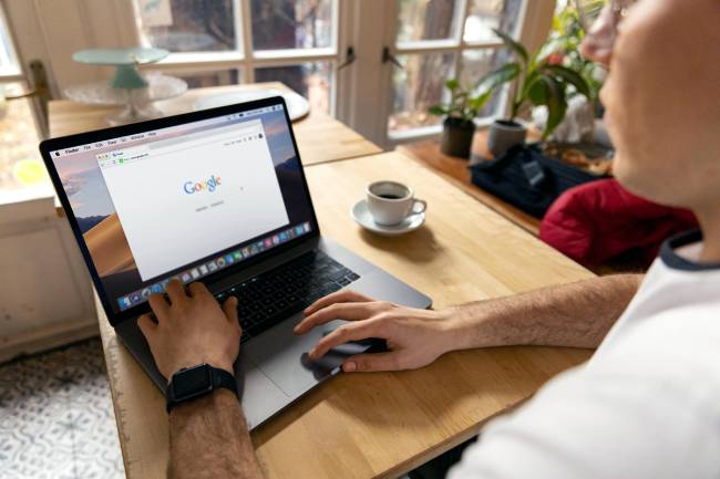 Zu sehen sind Hände, die einen Laptop bedienen, darauf ist Google aufgerufen. Der Google-Kalender bietet die Funktion der Online-Terminbuchung. Bild: Pexels/Firmbee.com
