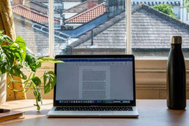 Zu sehen ist ein MacBook auf einem Schreibtisch auf dem Word aufgerufen ist. Viele Nutzer fragen sich aktuell: Wie lange kann man Office 2016 noch nutzen? Bild: Unsplash/Mikey Harris