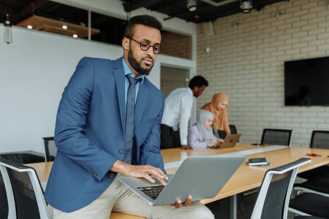 Zu sehen ist ein Konferenzraum, im Vordergrund ist ein Mann mit Laptop, der dank Exchange Server 2016 vielleicht gerade seine E-Mails prüft. Bild: Pexels/Thirdman