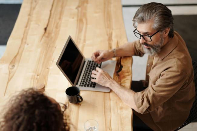 Zu sehen sind zwei Kollegen, die am Laptop sitzen und eine Prozessbeschreibung erstellen wollen. Bild: Pexels/Edmond Dantès