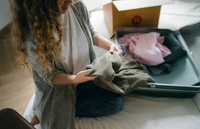 Zu sehen ist eine Frau, die einen Koffer packt. Sie muss bei der Arbeit noch die Urlaubsübergabe abschließen. Bild: Pexels/Ketut Subiyanto