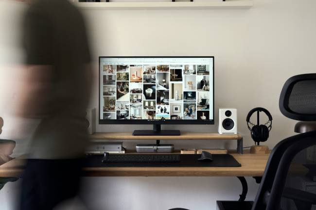 Zu sehen ist ein Home-Office-Setup, davor eine verschwommene Person. Vielleicht wird hier gemietete IT-Ausstattung genutzt. Bild: Unsplash/Lasse Jensen