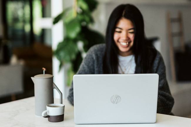 Zu sehen ist eine fröhliche Frau am Laptop. Dank Zwischenablage geht ihr die Arbeit leicht von der Hand. Bild: Unsplash/Windows