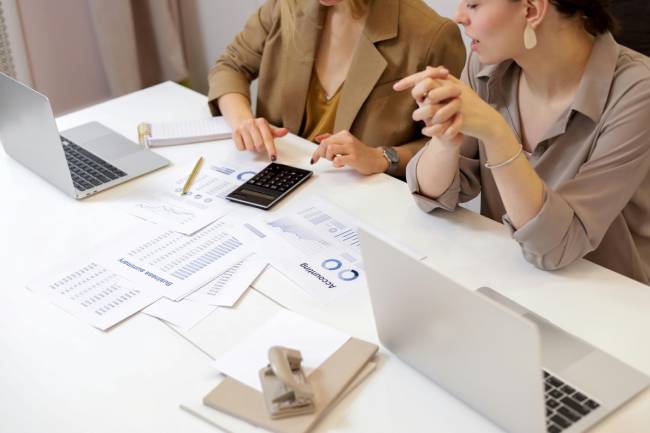 Zu sehen sind zwei Frauen bei der Zusammenarbeit, unter anderem mit Laptops. Es geht um die Produkthaftungsrichtlinie. Bild: Pexels/Artem Podrez