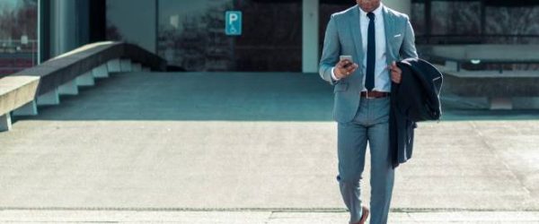 Zu sehen ist ein Geschäftsmann mit einem Smartphone. Vielleicht führt er einen schnellen E-Mail-Check durch. Bild: Unsplash/Bram Naus