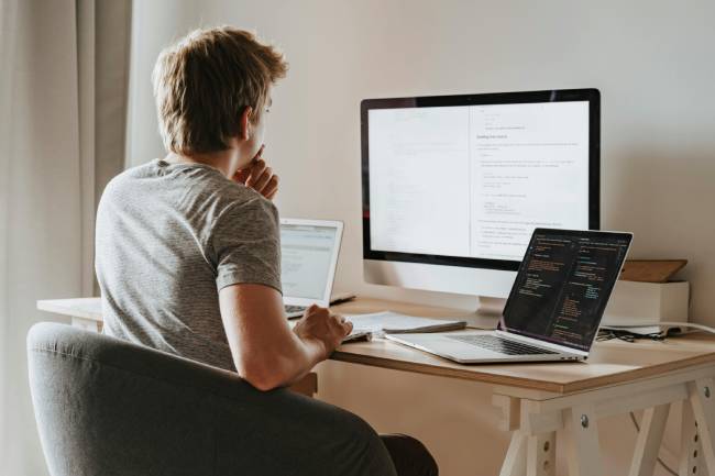 Zu sehen ist ein Mann der vor drei Bildschirmen sitzt und vermutlich gerade Opfer von DeepSeek-Malware geworden ist. Bild: Pexels/olia danilevich