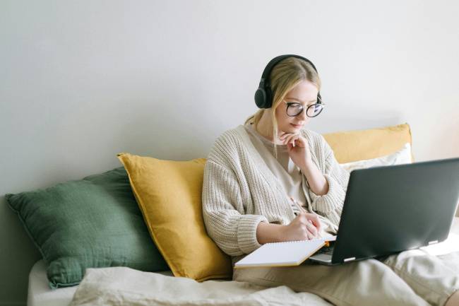Zu sehen ist eine Frau die auf der Couch am Laptop womöglich Desinformation im Netz liest. Bild: Pexels/Ivan Samkov