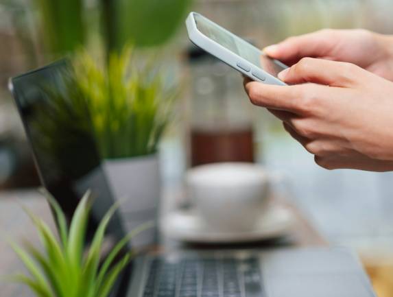 Zu sehen ist ein Handy und ein Laptop auf denen Fake-Profile von Führungskräften entdeckt werden. Bild: Unsplash/Jakub Żerdzicki
