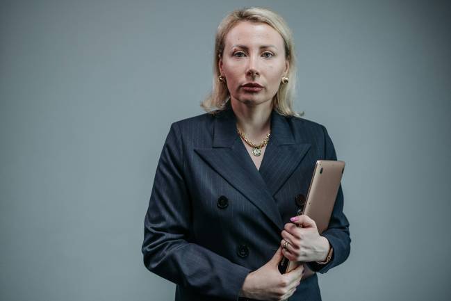 Eine Frau blickt ernst in die Kamera mit ihren Laptop in der Hand sie ist gerade einem Fake Profil von Führungskräften auf die Schliche gekommen. Bild: Pexels/Pavel Danilyuk